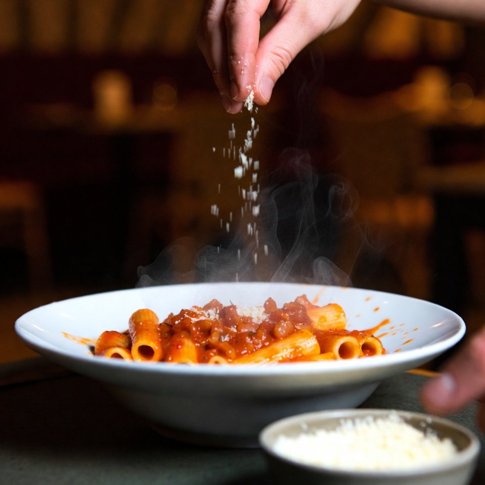 Steaming amatriciana bowl with hand grating pecorino cheese