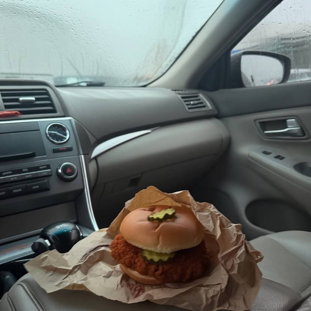 Blurry spicy chicken sandwich on foggy car passenger seat