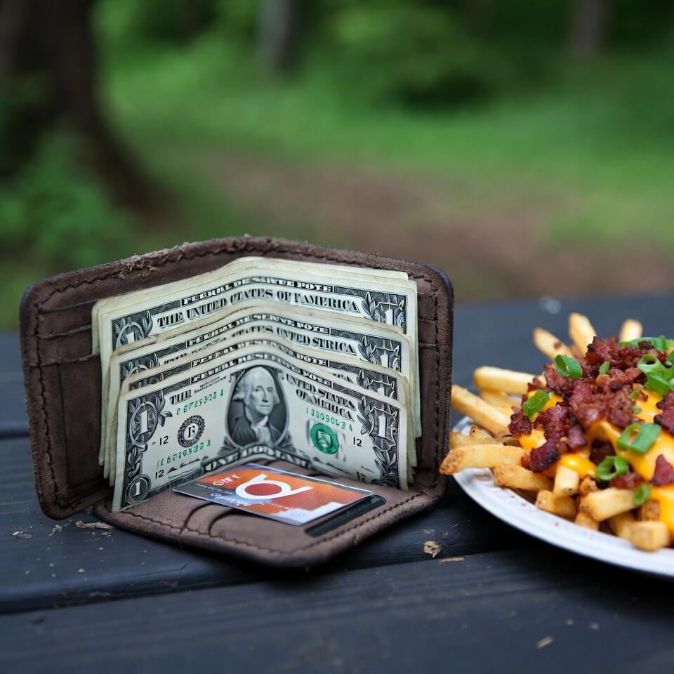 Worn wallet with singles open beside half-eaten loaded fries
