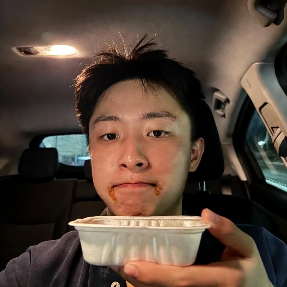 Post-meal car selfie with sauce on chin holding empty container.